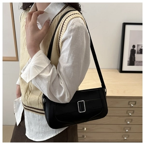 Minimalist black matte leather underarm bag with silver square buckle worn by a model
