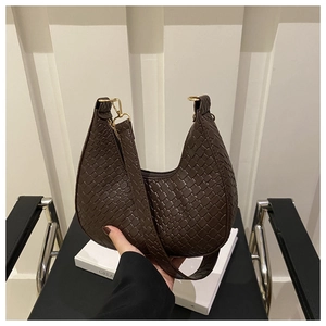 Detail shot of dark brown woven crescent underarm bag with matte leather and gold metal hardware