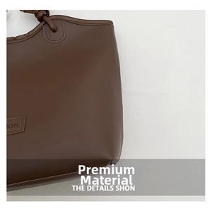 Detail of premium leather texture and embossed side patch on dark brown tote bag