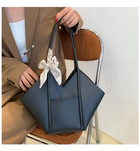 Detail of a black geometric leather tote bag featuring a decorative printed scarf handle