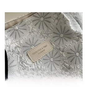 Macro detail of 3D floral texture and embossed leather brand tag on the tote bag