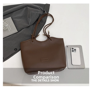 Detail view of large dark brown tote bag with leather tag and decorative knot straps