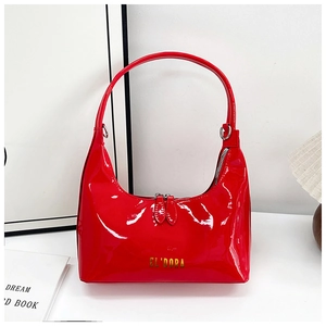 Detail view of red patent leather handbag with gold lettering and dual zipper closure