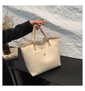 Detail of large beige tote bag with contrasting khaki straps and front snap pocket