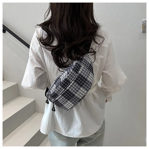 Rear view of minimalist black and white plaid chest bag with adjustable strap on model