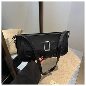 Detail of minimalist black rectangle shoulder bag with silver buckle on beige knit background