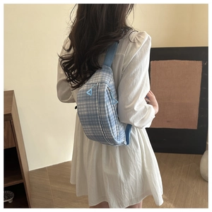Detail of blue plaid corduroy waist bag with adjustable strap shown on model's back