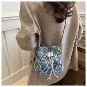 Dettaglio borsa a secchiello in denim blu con trama trapuntata e finiture dorate