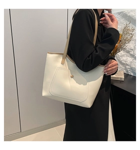 Detail of minimalist cream tote bag with contrast brown strap and metal snap button