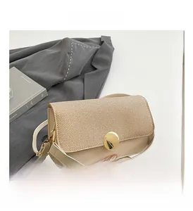 Detail of beige shoulder bag with straw texture and golden circular metallic buckle