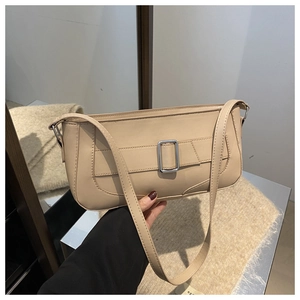 Detail of beige faux leather baguette bag with silver buckle and structured shoulder strap