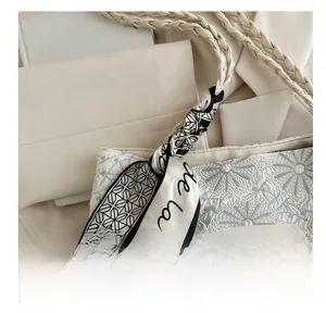 Close-up of white tote bag with daisy embroidery and a black and white scarf detail