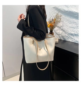 Close-up of cream tote bag with khaki trim and metal buckle pocket detail