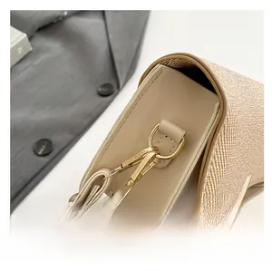 Detail of a beige leather and woven saddle bag side view with gold hardware accents