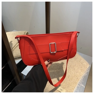 Detail of red leather baguette shoulder bag with stylish wide strap and silver buckle