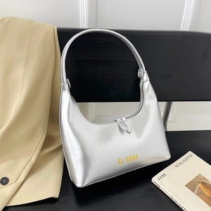 Glossy silver metallic hobo bag with yellow logo on a chair next to a trench coat