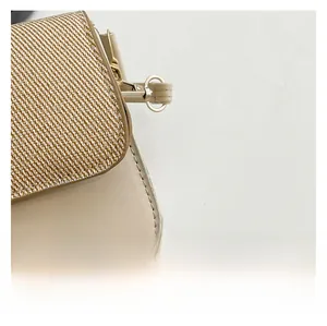 Detail of beige leather bag featuring golden diagonal weave texture and metallic clasp