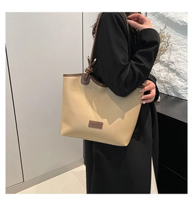 Detail of beige tote bag with brown handles and fashion leather patch for women