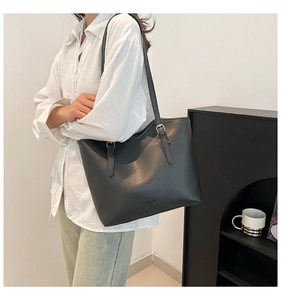 Minimalist black tote bag with slim shoulder straps and matte leather texture on a model