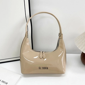 Glossy beige lacquer hobo bag with black letter logo in a minimalist home setting