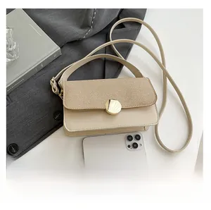 Detail view of woven leather bag flap with golden circular metal lock and phone for scale