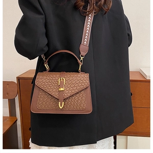 Detailed view of brown woven texture handbag with stylish geometric wide shoulder strap