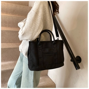 Detail of black canvas tote bag with metal rivets and adjustable shoulder strap