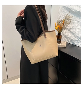 Detail of minimalist cream tote bag with contrast brown handle worn on the shoulder
