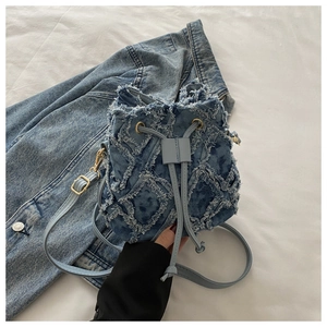 Vista dettagliata della trama in denim invecchiato e bordi sfrangiati sulla borsa blu