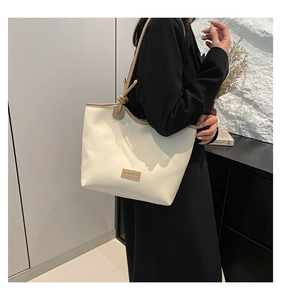 Macro detail of large cream leather tote bag with contrasting brown trim and fashion tag