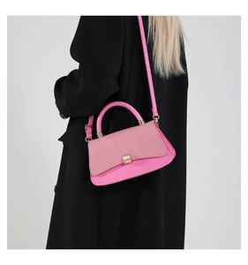 Detail of hot pink crossbody bag with woven texture flap and golden buckle on model