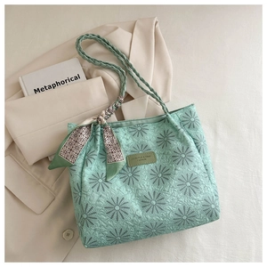 Detail of mint green quilted tote bag featuring sunflower pattern and woven handles