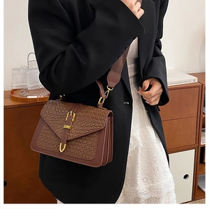 Close-up of retro brown woven texture flap bag with gold buckle and leather trim