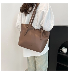 Brown leather tote bag shown from behind featuring adjustable gold buckles and fashion text