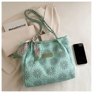 Detail of light green tote bag with daisy floral texture and woven handle decoration