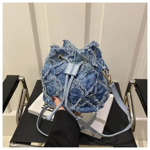 Dettaglio della borsa a secchiello in denim trapuntato con bordi sfrangiati e lacci in pelle