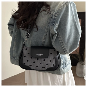 Détail d'un sac sous les bras en denim à pois avec petits nœuds et rabat en cuir
