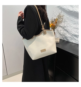 Detail view of cream tote bag with brown straps and contrast stitching on a model