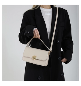 Vue détaillée du sac rectangulaire en cuir blanc cassé avec boucle ronde en métal doré