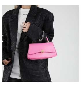 Borsa a tracolla in pelle rosa con base curva e catena d'argento indossata