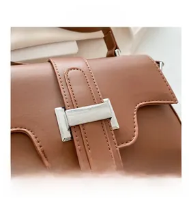 Close-up of brown PU leather bag featuring wave-edge flap and silver square metal clasp