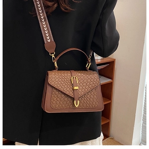 Detail of vintage brown crossbody bag featuring crocodile pattern and wide woven strap