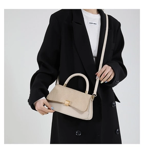 Detail of minimalist cream leather crossbody bag with textured woven flap and gold clasp