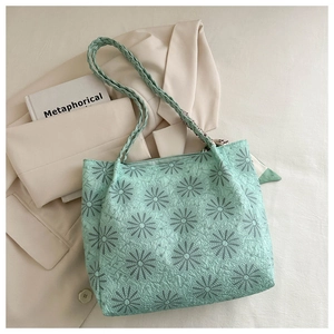 Detail of mint green tote bag featuring daisy embroidery and woven shoulder strap