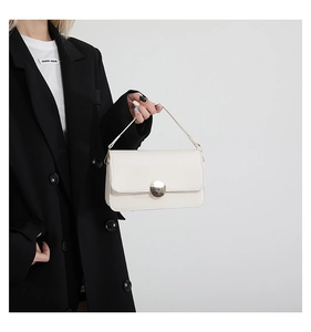 Détail du sac baguette blanc crème avec boucle ronde dorée et poignée en cuir élégante