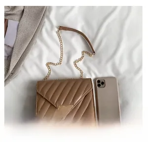 Detail der gesteppten Umhängetasche mit goldener Kette und Größenvergleich zum Handy