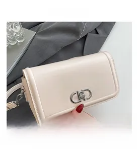 Close-up of the beige leather bag featuring a silver CD-style metal twist lock and stitching