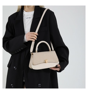 Detail of minimalist cream leather handbag with textured flap and gold square lock