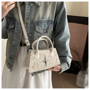 Detail of woven straw handbag with floral embroidery and star metallic charm