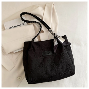 Detail of black tote bag featuring embossed floral texture and chic decorative scarf